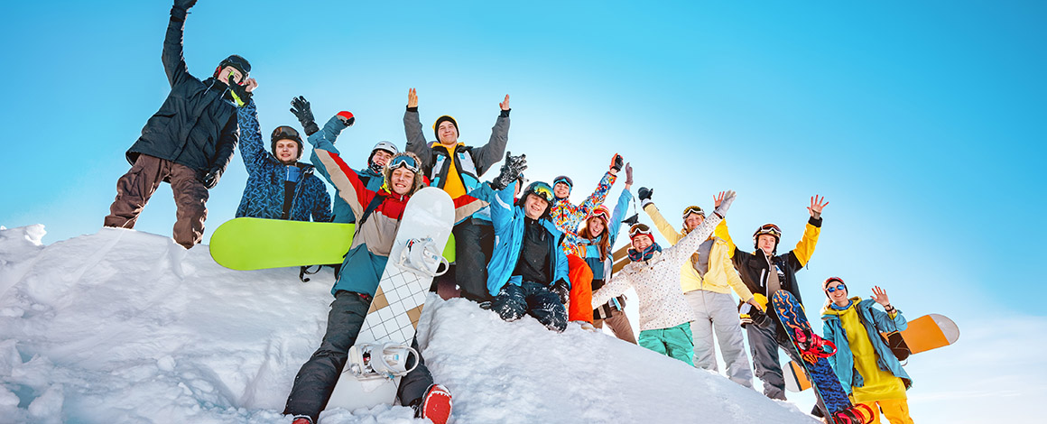 vriendengroep in de sneeuw op skivakantie met snowboard in de hand of op de rug