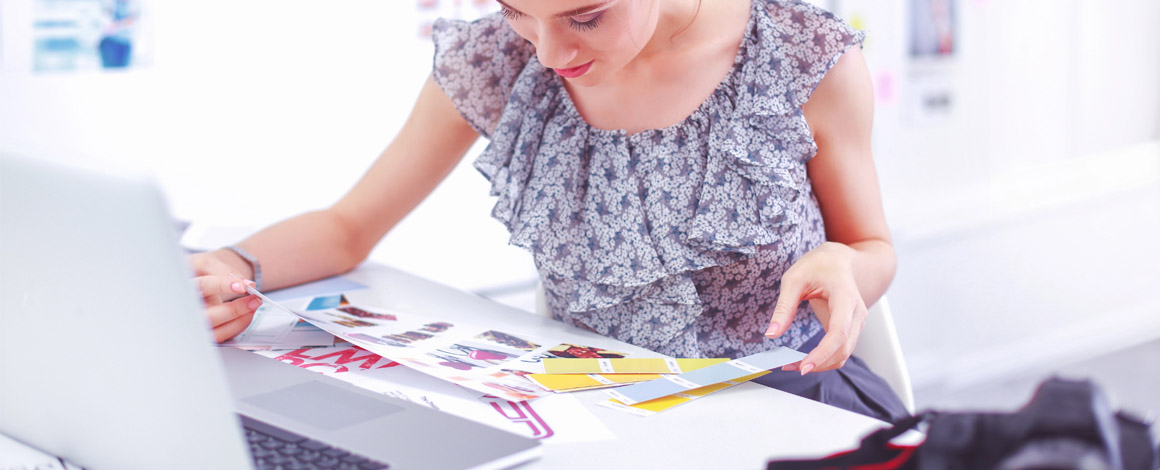 een vrouw is de kleuren op het drukwerk aan het vergelijken met kleurstalen