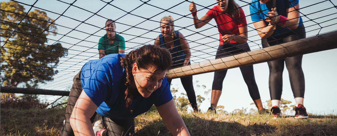 teambuilding activiteit waarbij iemand onder een net moet kruipen terwijl ze aangemoedigd wordt door omstaanders