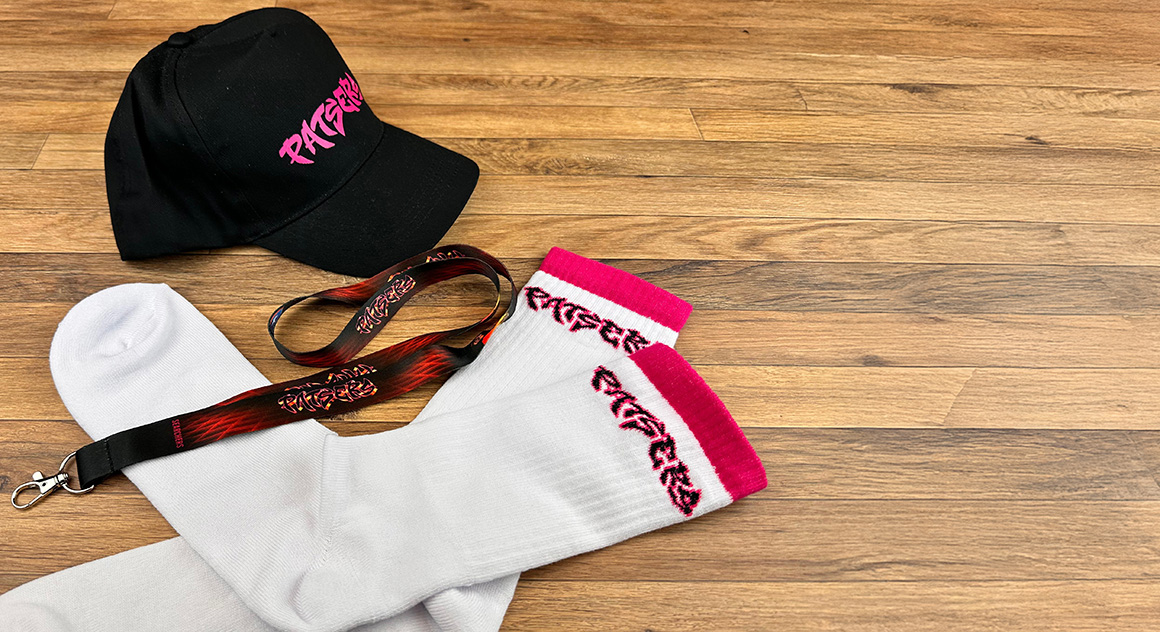 collectie van alle gadgets die door Maxevent gemaakt werden voor de filmpremiere van Patsers met een pet, lanyard en een paar sokken.