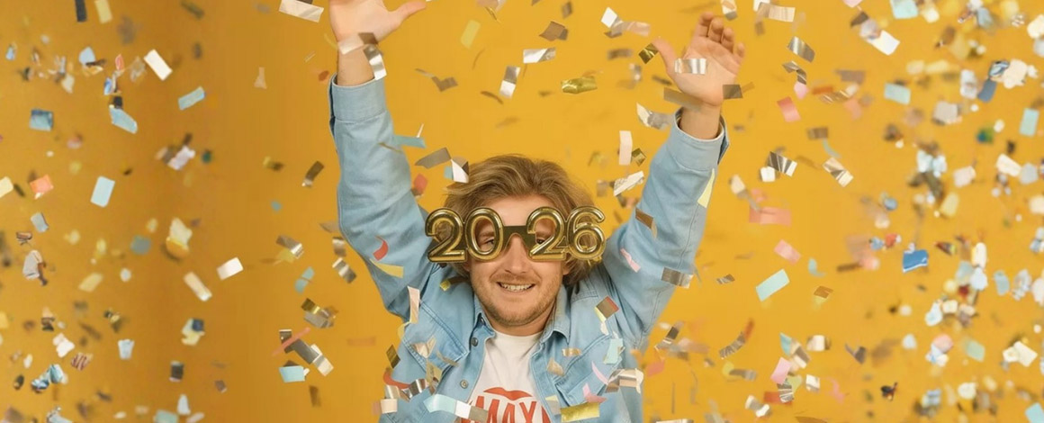 man met brilletje in vorm van 2026 voor een gele achtergrond terwijl confetti in de lucht dwarrelt